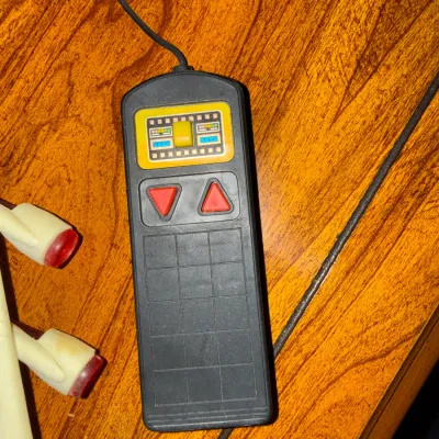 Sale Photo Thumbnail #323: Vintage handheld video game controller with directional buttons and numeric keypad grid, resting on a wooden surface.
