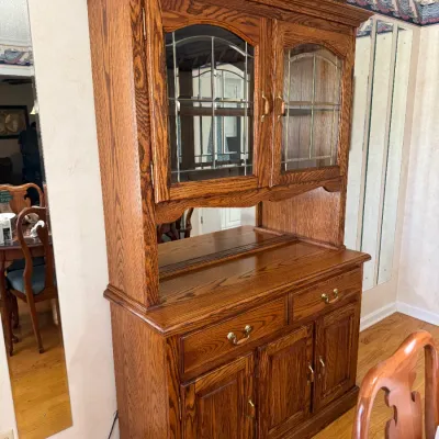 Sale Photo Thumbnail #189: Traditional golden oak hutch with leaded glass cabinet doors, mirrored open display shelf, two drawers, and lower cabinet storage.