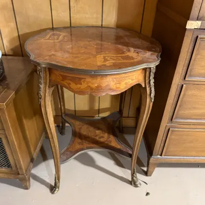 Sale Photo Thumbnail #383: French Provincial style marquetry accent table featuring floral wood inlay, brass mounts, cabriole legs, and a lower tier shelf.