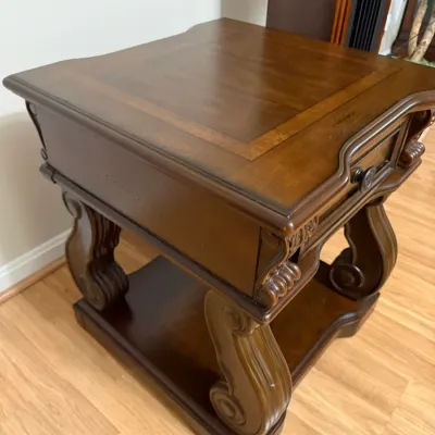 Sale Photo Thumbnail #16: Traditional dark wood end table featuring a single drawer, inset wood grain top, and carved scrollwork legs with a bottom shelf.