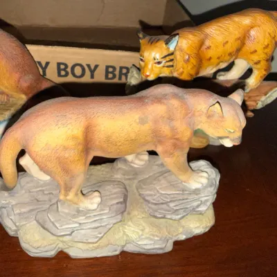 Sale Photo Thumbnail #290: Collection of painted ceramic wild cat figurines, including a cougar and bobcat mounted on rock-like bases.