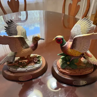Sale Photo Thumbnail #233: Pair of vintage ceramic pheasant figurines mounted on wooden display bases, featuring detailed painted feathers and naturalistic scenery.