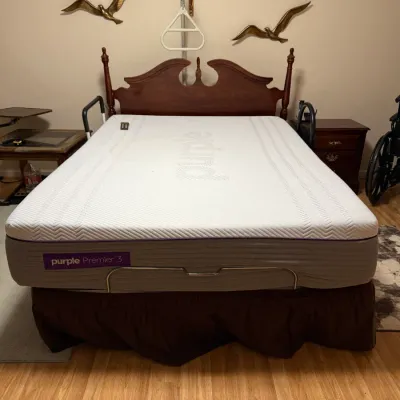 Sale Photo Thumbnail #123: Purple Premier 3 mattress on an adjustable bed frame set in a traditional dark wood headboard, equipped with side assist rails and an overhead trapeze bar.