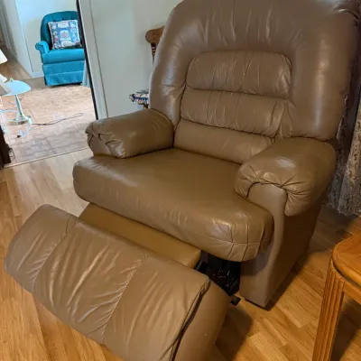 Sale Photo Thumbnail #88: Overstuffed taupe leather or faux-leather reclining armchair with an extended footrest.