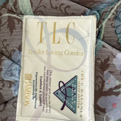 Sale Photo Thumbnail #94: Close-up of a Jamison Tender Loving Comfort mattress label sewn onto a floral patterned fabric.