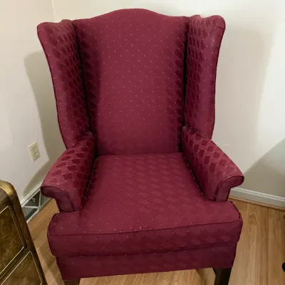 Sale Photo Thumbnail #96: Traditional wingback armchair upholstered in burgundy geometric patterned fabric, set on dark wood legs.