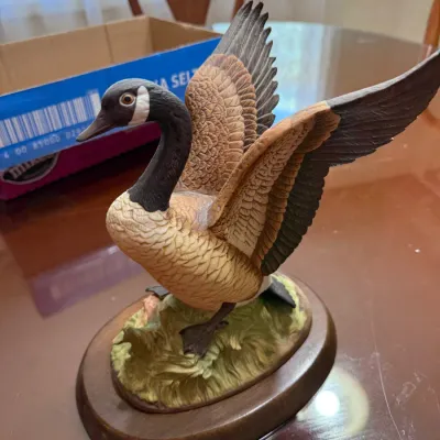 Sale Photo Thumbnail #282: Hand-painted porcelain Canada goose figurine with outstretched wings, mounted on a wooden display base.