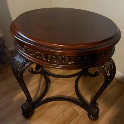 Sale Photo Thumbnail #81: Traditional round wood side table featuring carved scroll detailing along the apron and ornate cabriole-style metal legs.