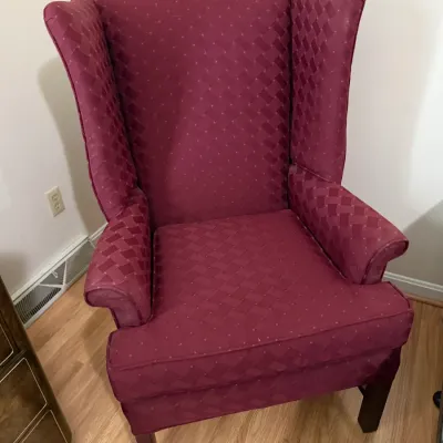 Sale Photo Thumbnail #95: Traditional wingback armchair upholstered in a burgundy patterned fabric, featuring wooden legs and rolled arms.