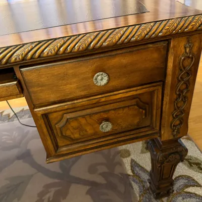 Sale Photo Thumbnail #59: Traditional wooden executive desk featuring a leather inlaid top, rope twist carved edges, ornamental corner overlays, and detailed knob hardware.