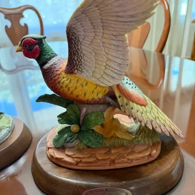Sale Photo Thumbnail #234: Hand-painted porcelain ring-necked pheasant figurine mounted on an oval wooden display base with a brass plaque.