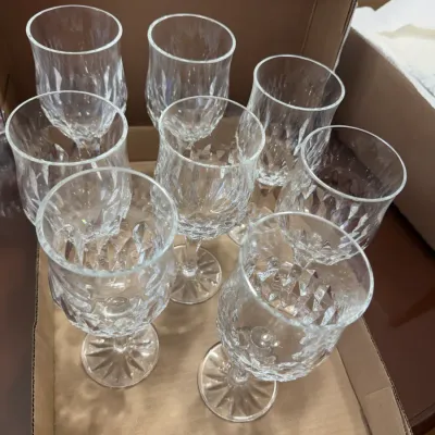 Sale Photo Thumbnail #314: Set of eight vintage crystal wine goblets with diamond-cut patterns and starburst bases, packed in a cardboard box.