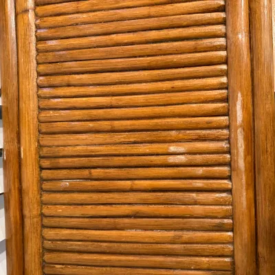 Sale Photo Thumbnail #132: Detail view of a vintage split-reed or bamboo furniture piece, showing wear and scuffing to the warm brown finish.