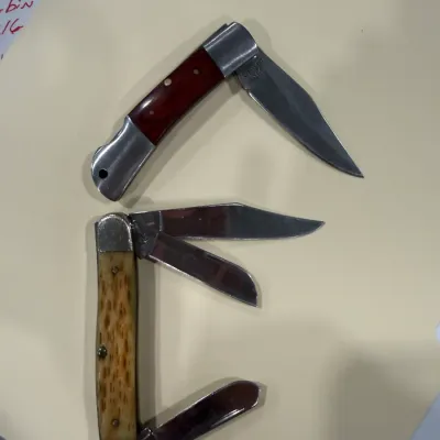 Sale Photo Thumbnail #417: Two vintage folding pocket knives, including a single-blade lockback knife with a reddish-brown wood handle and a multi-blade knife with a jigged bone handle.