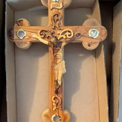 Sale Photo Thumbnail #336: Hand-carved olive wood crucifix featuring a detailed corpus figure and four round glass-encased relic compartments, presented in a cardboard box.