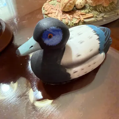 Sale Photo Thumbnail #253: Hand-painted duck decoy figurine featuring blue and grey detailing, displayed on a wooden surface.