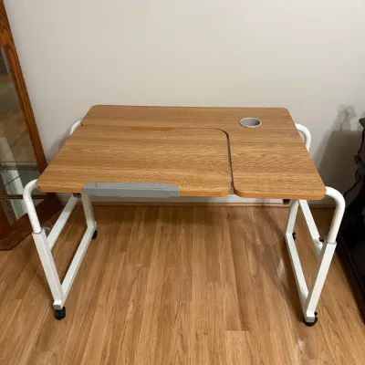 Sale Photo Thumbnail #24: Modern mobile overbed or standing laptop desk featuring a light wood laminate top, white metal frame on casters, and a built-in cup holder.