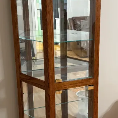 Sale Photo Thumbnail #20: Tall oak display curio cabinet featuring glass side panels, glass shelving, and brass accents.
