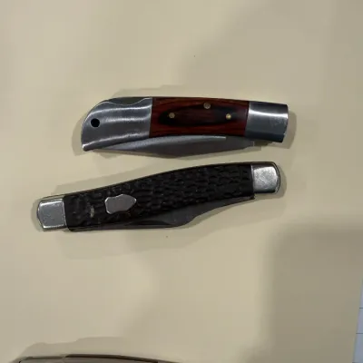 Sale Photo Thumbnail #414: Collection of three folding pocket knives featuring wood inlay and textured jigged handles with stainless steel bolsters.