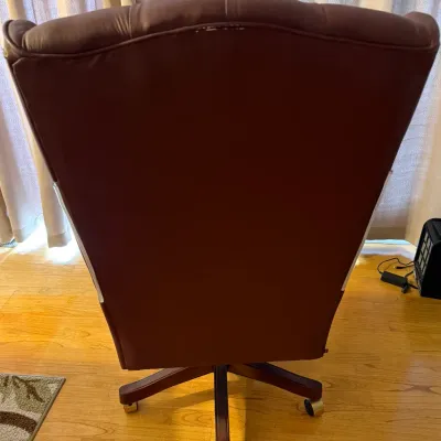 Sale Photo Thumbnail #68: Back view of a burgundy leather executive office chair on a wooden five-star caster base.