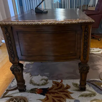 Sale Photo Thumbnail #60: Traditional carved wooden executive desk featuring a leather inlay top, rope-twist trim, and ornate detailed legs.