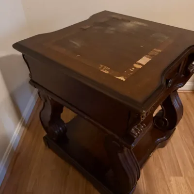 Sale Photo Thumbnail #14: Dark wood traditional side table featuring ornate carved legs, showing significant wear and peeling veneer on the top surface.