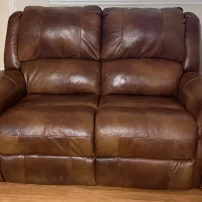 Sale Photo Thumbnail #9: Brown leather reclining loveseat featuring nailhead trim detailing along the rolled armrests.