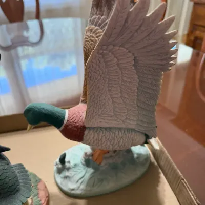 Sale Photo Thumbnail #245: Hand-painted porcelain mallard duck figurine in flight, featuring detailed feather textures and a painted oval base.