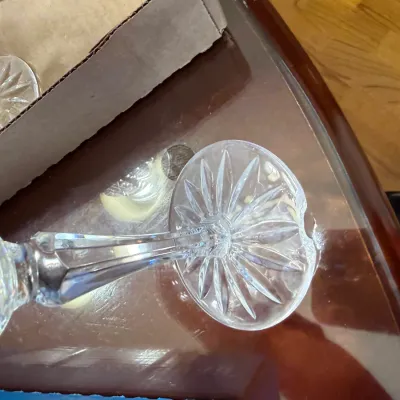 Sale Photo Thumbnail #313: Close-up view of the starburst-patterned base and faceted stem of a crystal stemware glass with a noticeable chip on the foot edge.