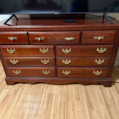 Sale Photo Thumbnail #127: Traditional cherry wood nine-drawer dresser featuring brass batwing hardware and an carved fan detail on the center drawer.
