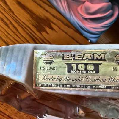 Sale Photo Thumbnail #330: Close-up of a vintage Jim Beam 100 Months Old Kentucky Straight Bourbon Whiskey decanter label by Regal China.