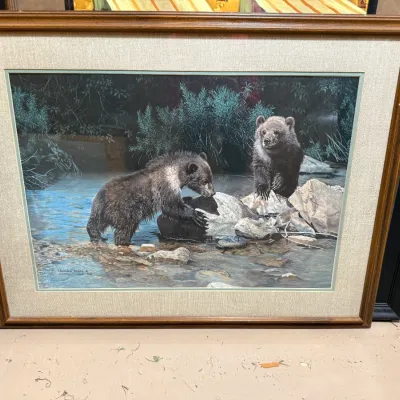 Sale Photo Thumbnail #395: Framed wildlife art print depicting two bear cubs in a stream, housed in a wood frame with a textured fabric mat.