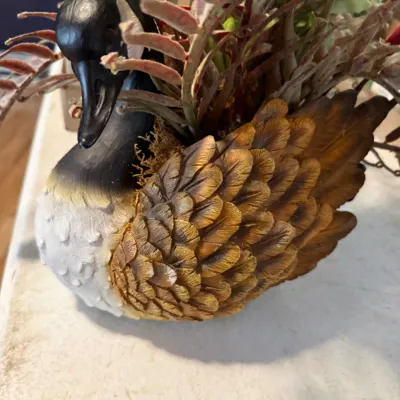 Sale Photo Thumbnail #228: Vintage Canada goose planter figurine made of painted resin or composite, filled with faux foliage.