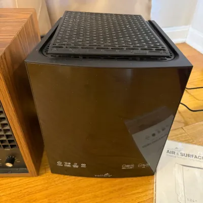 Sale Photo Thumbnail #180: Vollara Air & Surface Pro portable air purifier with black glossy finish, accompanied by its instruction manual.