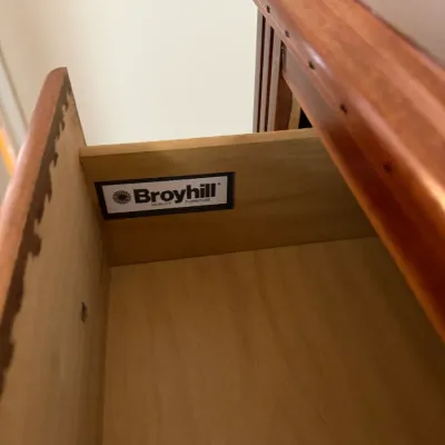 Sale Photo Thumbnail #129: Open wooden furniture drawer with dovetailed joinery, displaying the Broyhill Furniture brand logo inside.