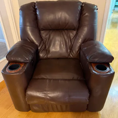 Sale Photo Thumbnail #70: Contemporary dark brown leather theater-style recliner featuring plush cushioning and integrated armrest cup holders with faux-wood trim.