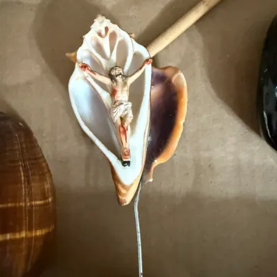 Sale Photo Thumbnail #346: Vintage seashell crucifix souvenir featuring a carved sea shell with a miniature figure of Jesus and a wire hanger.