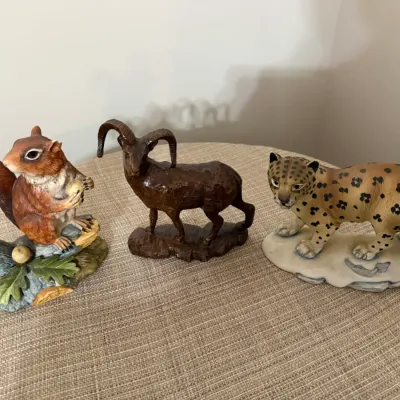 Sale Photo Thumbnail #339: Trio of animal figurines including a painted squirrel on a branch, a carved wood-look bighorn sheep, and a porcelain leopard.