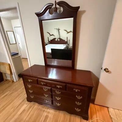 Sale Photo Thumbnail #373: Traditional mahogany dresser featuring a bonnet-top attachment with a central urn finial and rectangular mirror over multiple drawers with brass batwing pull handles.