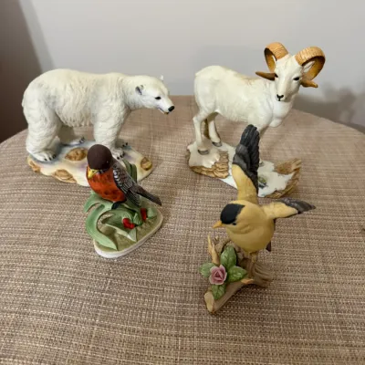 Sale Photo Thumbnail #344: Collection of four porcelain animal figurines including a polar bear, bighorn sheep, robin, and goldfinch, all in good condition.