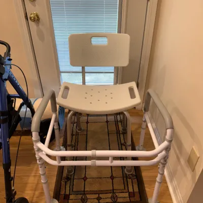 Sale Photo Thumbnail #137: Adjustable plastic and aluminum shower chair with backrest, positioned behind a stand-assist safety frame.