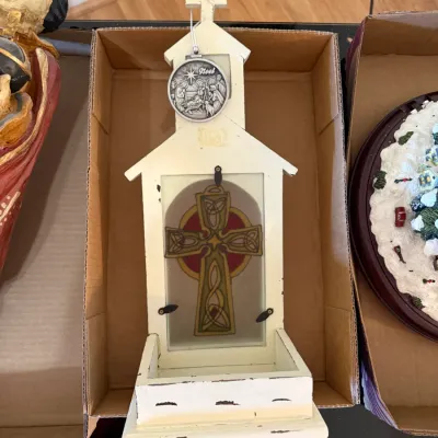 Sale Photo Thumbnail #158: Distressed cream-painted wooden church-shaped holy water font featuring a Celtic cross glass insert and hanging silver-tone Noël medallion.