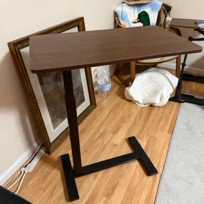 Sale Photo Thumbnail #377: Adjustable height overbed or side table with a dark wood-grained top and black metal C-frame base.
