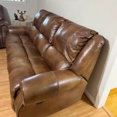 Sale Photo Thumbnail #7: Contemporary brown faux-leather reclining sofa featuring nailhead trim detailing along the front arms.