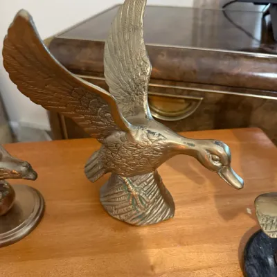Sale Photo Thumbnail #363: Vintage solid brass figurine of a duck or goose in flight, featuring detailed feather textures and natural patina.