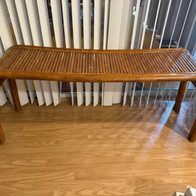 Sale Photo Thumbnail #131: Vintage bentwood and rattan pencil reed waterfall bench with a slatted seat, sitting on a laminate wood floor in front of vertical blinds.