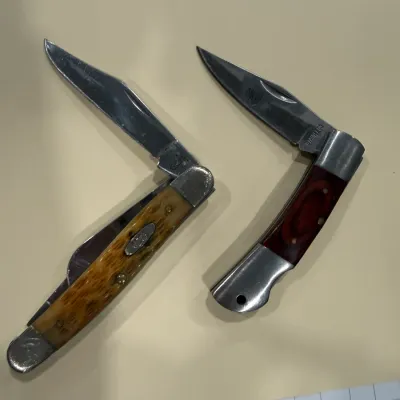 Sale Photo Thumbnail #416: Pair of vintage folding pocket knives, including a Case XX knife with a jigged bone handle and a lockback knife with wood grain inlay, showing light wear.