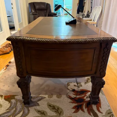 Sale Photo Thumbnail #58: Traditional wooden executive desk featuring a brown leather inlay top, carved rope molding along the apron, and detailed fluted legs.