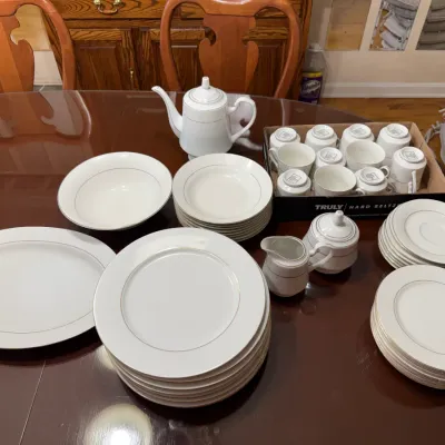 Sale Photo Thumbnail #297: Large white porcelain china service with silver trim, including dinner plates, salad plates, teacups, saucers, a teapot, creamer, sugar bowl, and serving platter.
