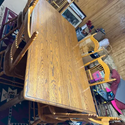 Sale Photo Thumbnail #409: Traditional golden oak dining table set with six spindle-back chairs featuring turned detail legs and finials.